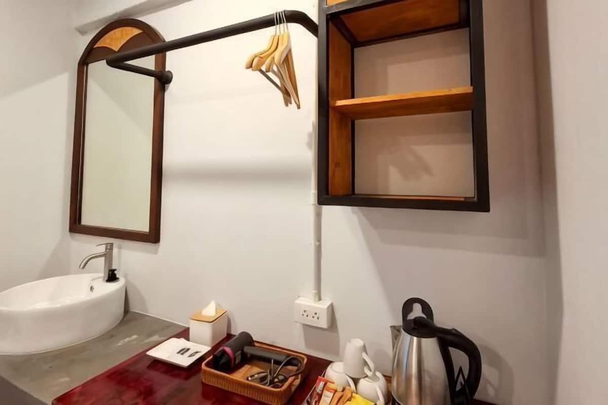 Une salle de bain avec un lavabo blanc, un miroir, un porte-serviettes et une étagère en bois.