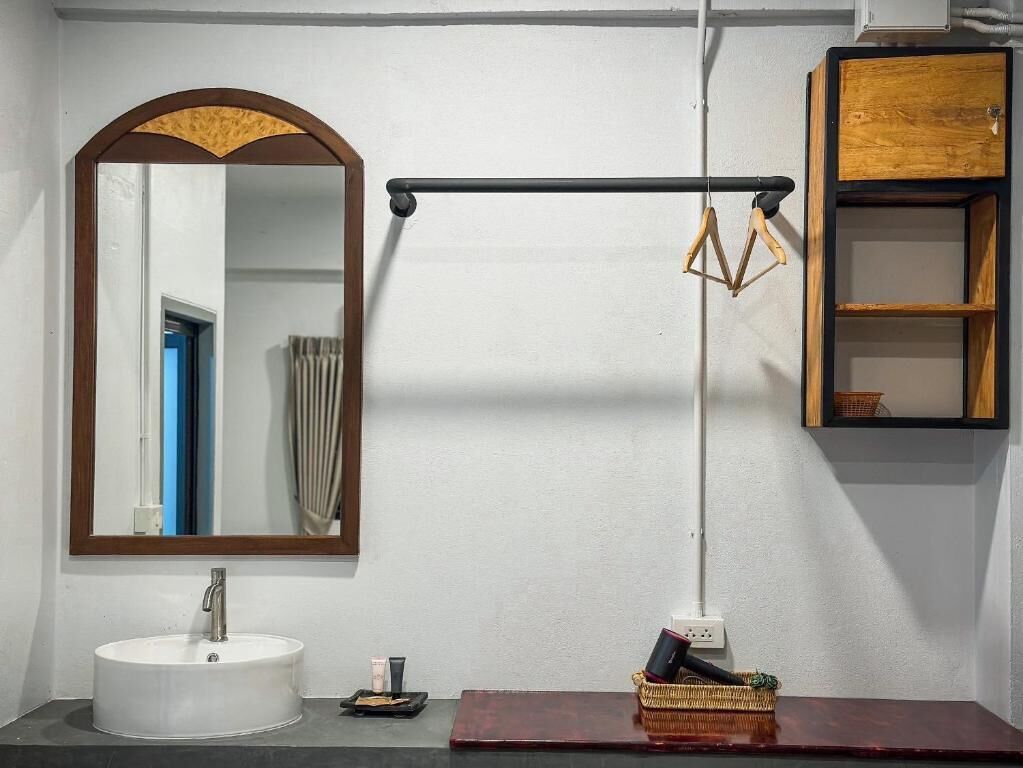 A bathroom with a white sink, a mirror with a wooden frame, a towel rack, and a wooden cabinet.