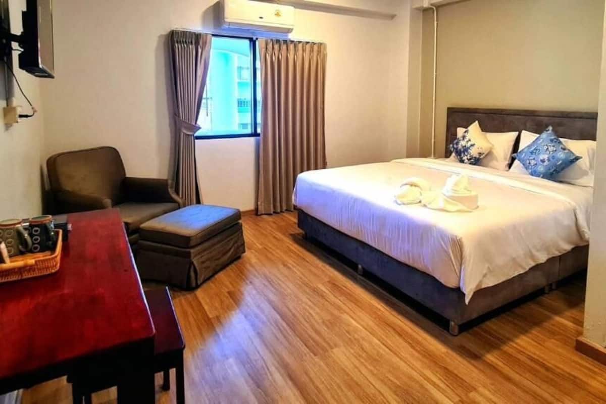 Une chambre d’hôtel avec un lit, un bureau, une chaise et une fenêtre avec des rideaux.