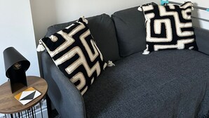 A modern living room with a grey sofa, two patterned throw pillows, a black lamp, and two framed botanical prints on the wall. - Flat 5 - Eign St. Hereford (Herefordshire)