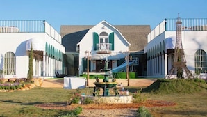 A building with a central fountain, a replica of the Eiffel Tower, and a garden with a circular flower bed.