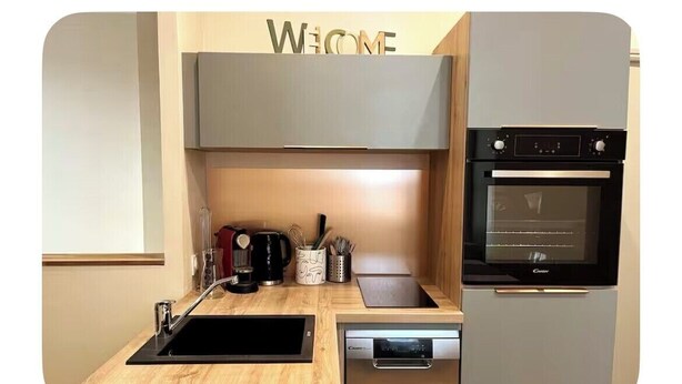 Een moderne keuken met een inbouwoven, vaatwasser en een houten aanrechtblad.