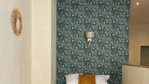 Een hotelkamer met een bed, een behang met patroon en een kleine lamp.