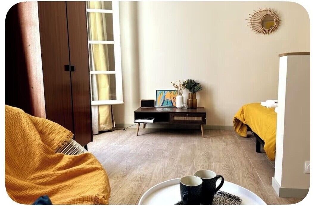 Een kamer met een bed, een nachtkastje met lamp, een fotolijst en een raam met gordijnen.