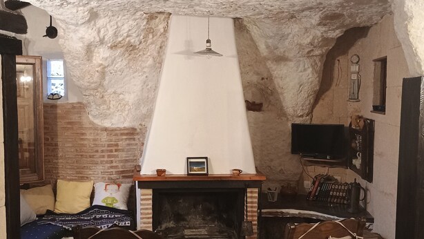 Ein rustikaler Raum mit Kamin, zwei Schaukelstühlen, einer Backsteinwand und einem an der Wand befestigten Fernseher.