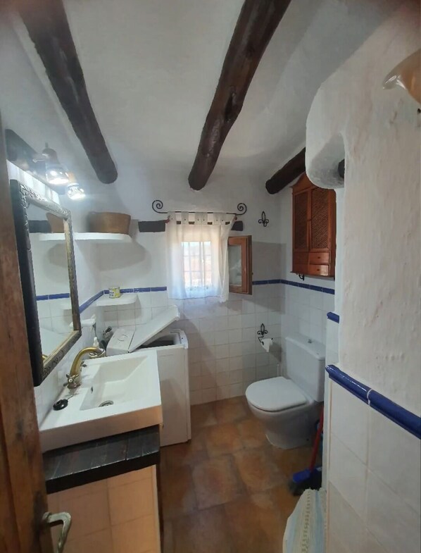 A bathroom with a sink, toilet, and mirror.