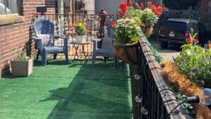 A courtyard with artificial green turf, outdoor seating, and potted plants.