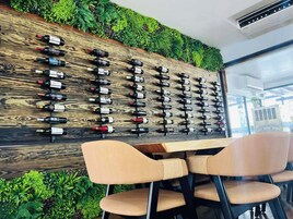 Una botellaera de pared con varias botellas, un panel de madera y un área de estar con sillas.