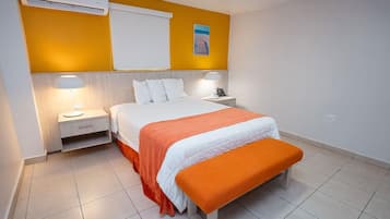 Una habitación de hotel con cama, mesitas de noche y un equipo de aire acondicionado.
