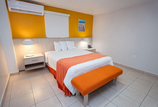 A hotel room with a bed, nightstands, and an air conditioning unit.