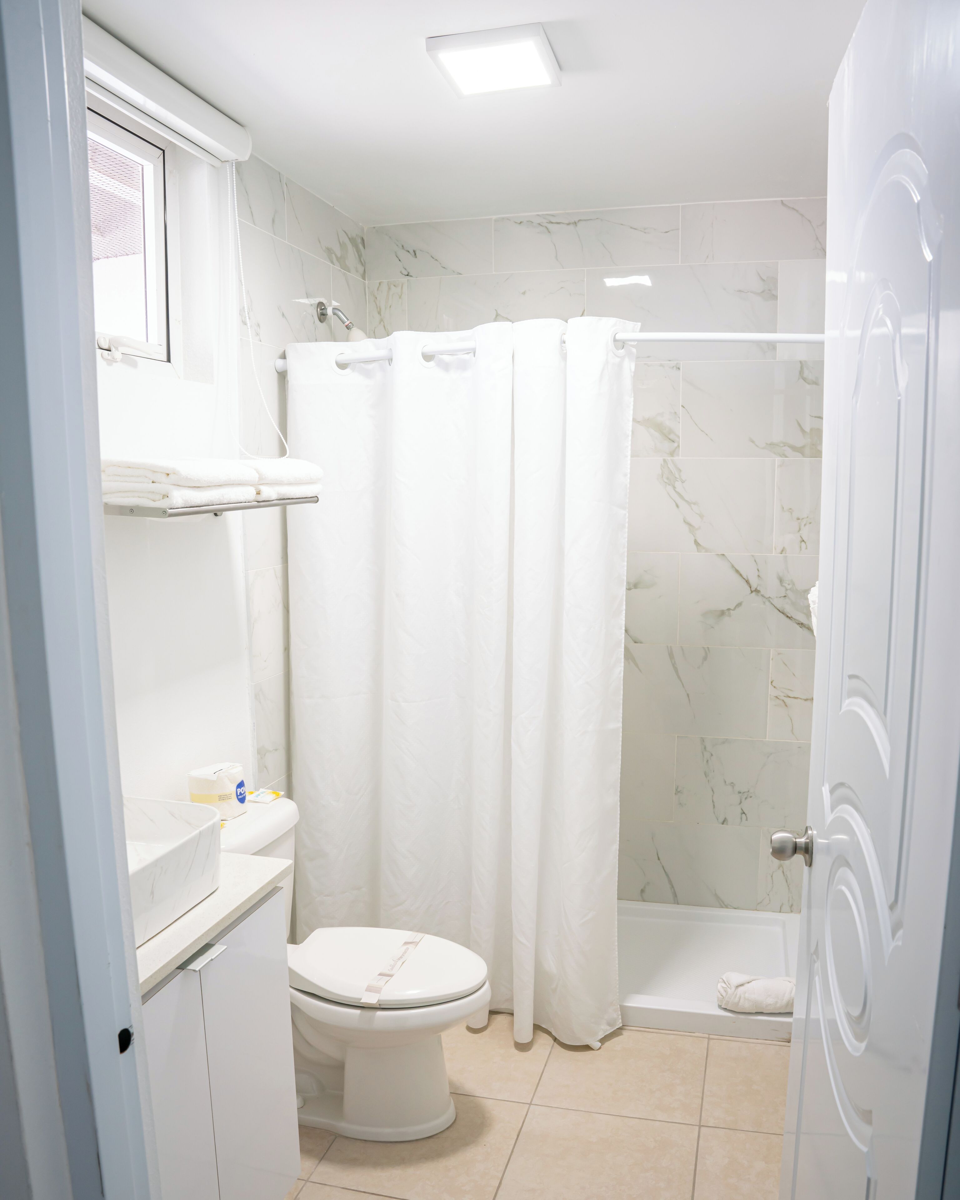 A bathroom with a toilet, a shower, and a sink.