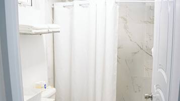 A bathroom with a toilet, a shower, and a sink.