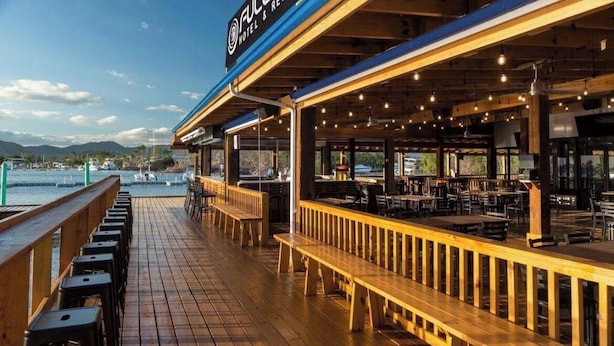 Un restaurant situé au bord de l’eau, doté d’une terrasse en bois et offrant une vue sur le port de plaisance.
