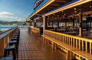 Un restaurante frente al agua con terraza de madera y vistas al puerto deportivo.