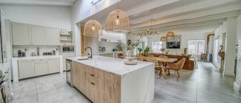 Cozinha moderna com ilha central, armários de madeira e iluminação pendente.