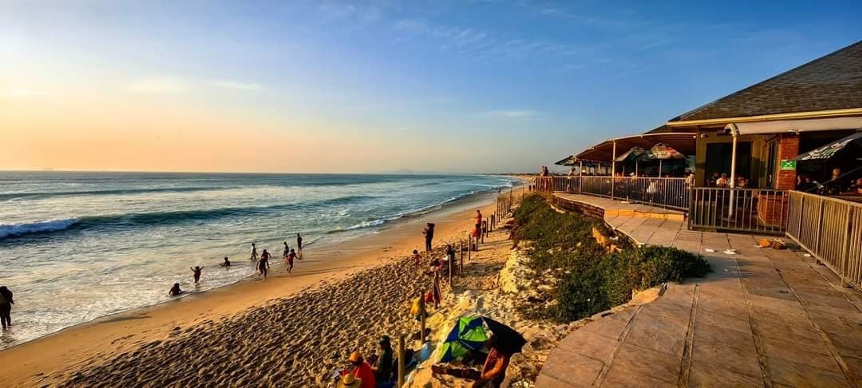 A beachside restaurant with outdoor seating overlooking the ocean.
