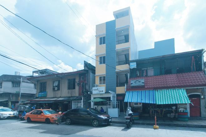 A street view with a multi-story building, a storefront with a blue awning, and a parked car.