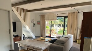 A modern living room with a wooden table, two chairs, a grey sofa, and a staircase leading to another level. - CASITA LATINA - Adults Only (Saint Genis des Fontaines)
