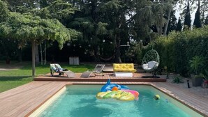A rectangular swimming pool with a wooden deck surrounding it. There are lounge chairs and a hammock in the background. - CASITA LATINA - Adults Only (Saint Genis des Fontaines)