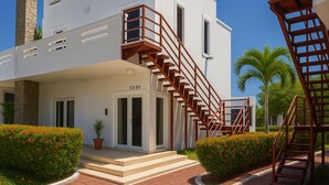 A modern building with a white facade, a numbered entrance, and a wooden staircase. - Barmel Villa Rooms (Roatan)