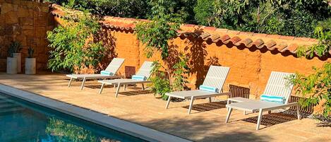 A poolside area with lounge chairs and a stone wall.