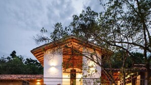 Una casa moderna con fachada de piedra, una pérgola de madera y una chimenea de piedra.