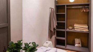 A compact bathroom with a white sink, a toilet, and a built-in shelving unit with towels and toiletries.