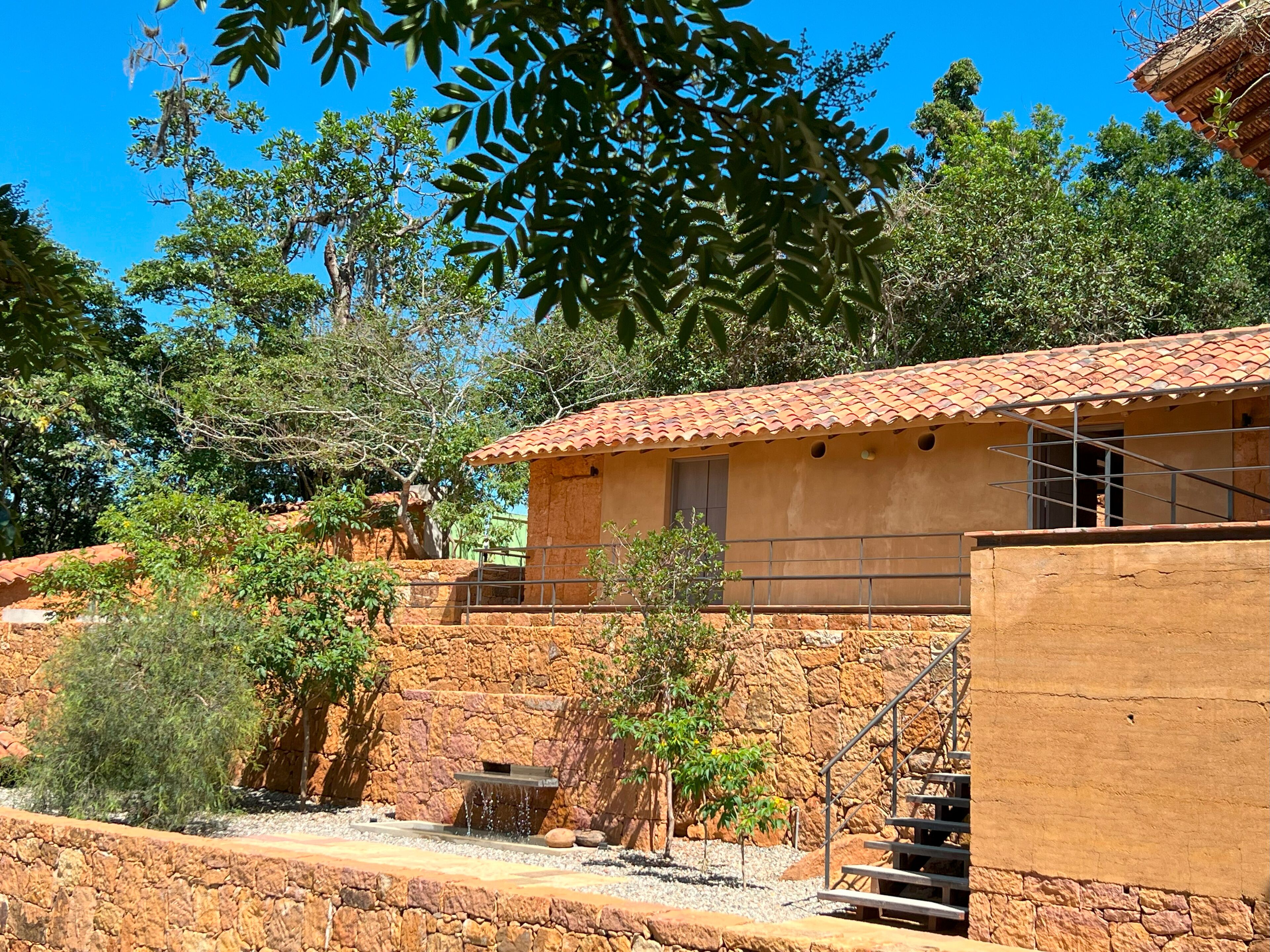 A rustic building with a tiled roof, stone walls, and a small waterfall feature.