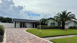A residential property with a paved driveway, a well-maintained lawn, and a house with a dark roof and light walls.