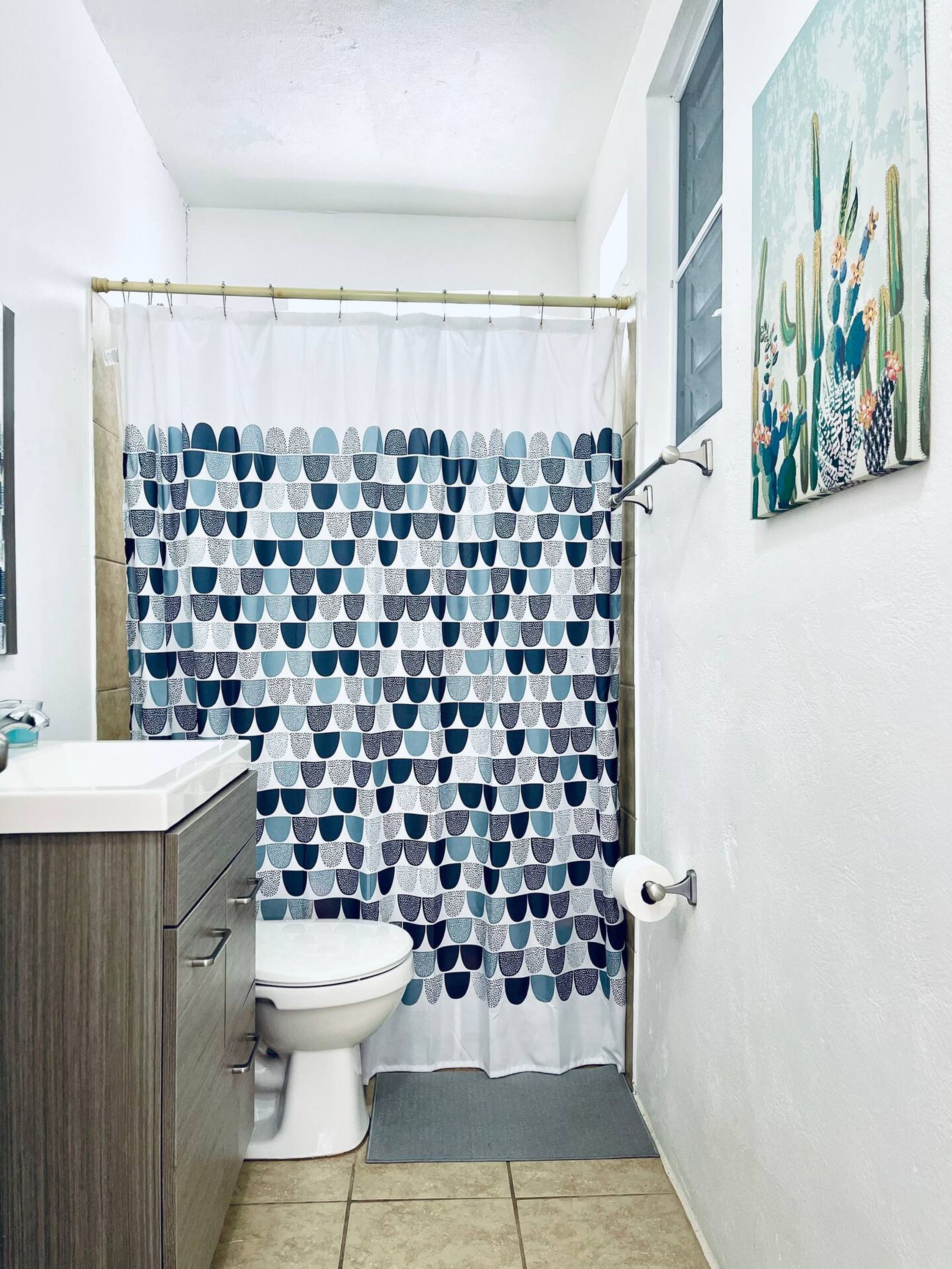 Et badeværelse med toilet, håndvask og bruseforhæng med et geometrisk mønster.