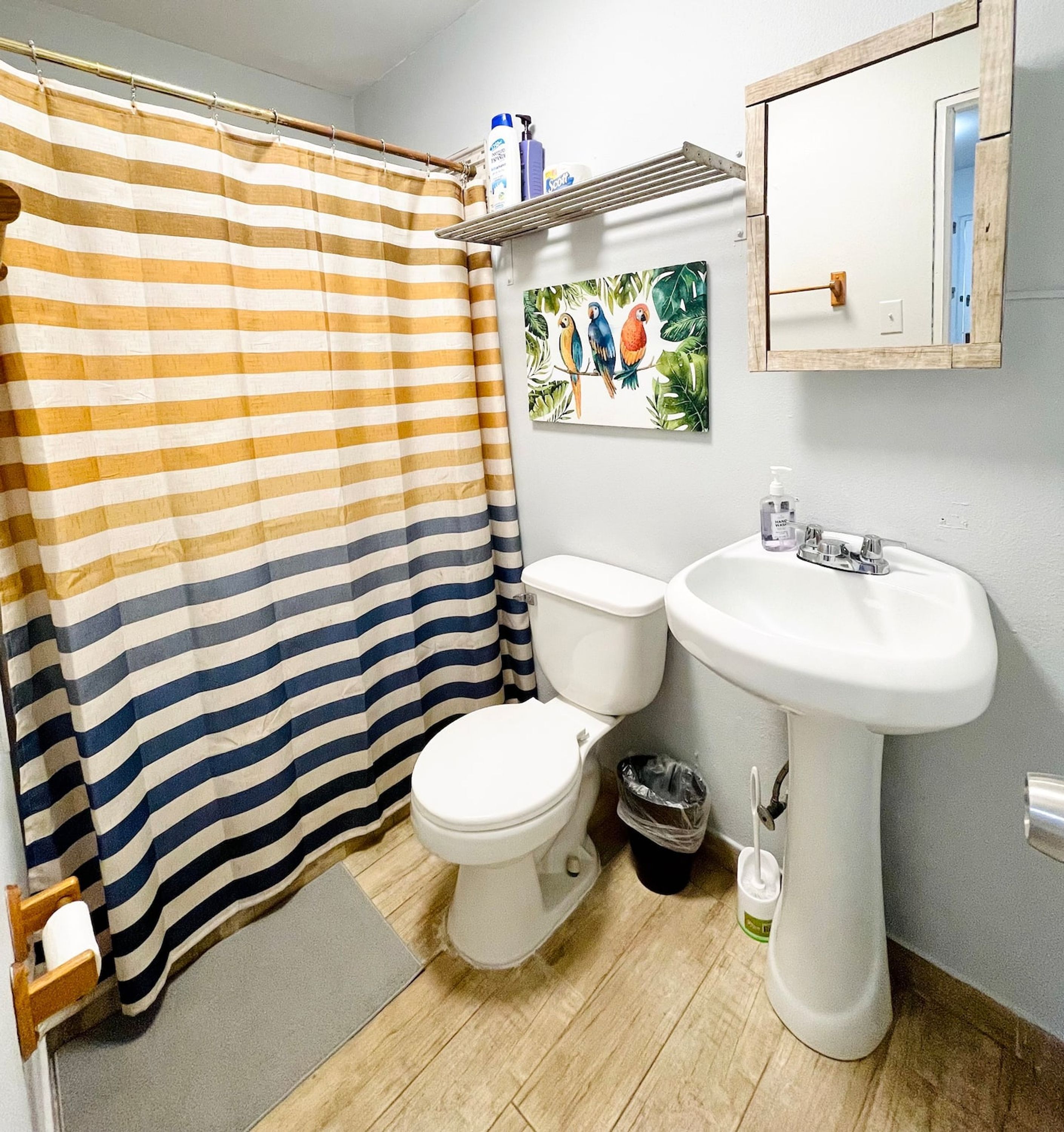 Un baño con cortina de ducha a rayas, un inodoro, un lavabo y un espejo.