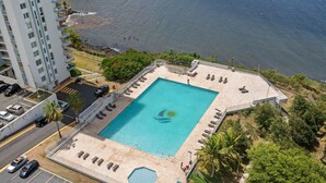 Ett flygbildsfoto av ett hotell med en swimmingpool, en parkeringsplats och utsikt över havet.