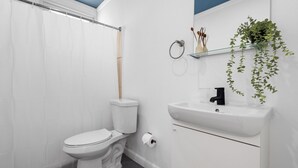 A bathroom with a toilet, sink, and shower curtain. - 101condado65avenue-bl (San Juan)
