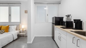A compact, modern kitchen with white cabinetry, a wooden countertop, and essential appliances like a microwave and coffee maker. - 101condado65avenue-bl (San Juan)