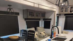 Cuina moderna amb illa central, armaris integrats i zona de menjador amb taula i cadires.