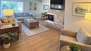 A modern living room with a fireplace, a sofa, a coffee table, and a TV.