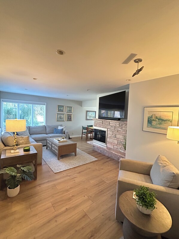 A modern living room with a fireplace, a sofa, a coffee table, and a TV.