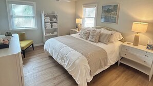 A bedroom with a bed, bedside tables, a chair, a desk, and a wardrobe.