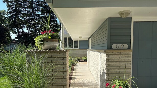 A house with a number 512 on the door, a covered porch, and potted plants on the steps.