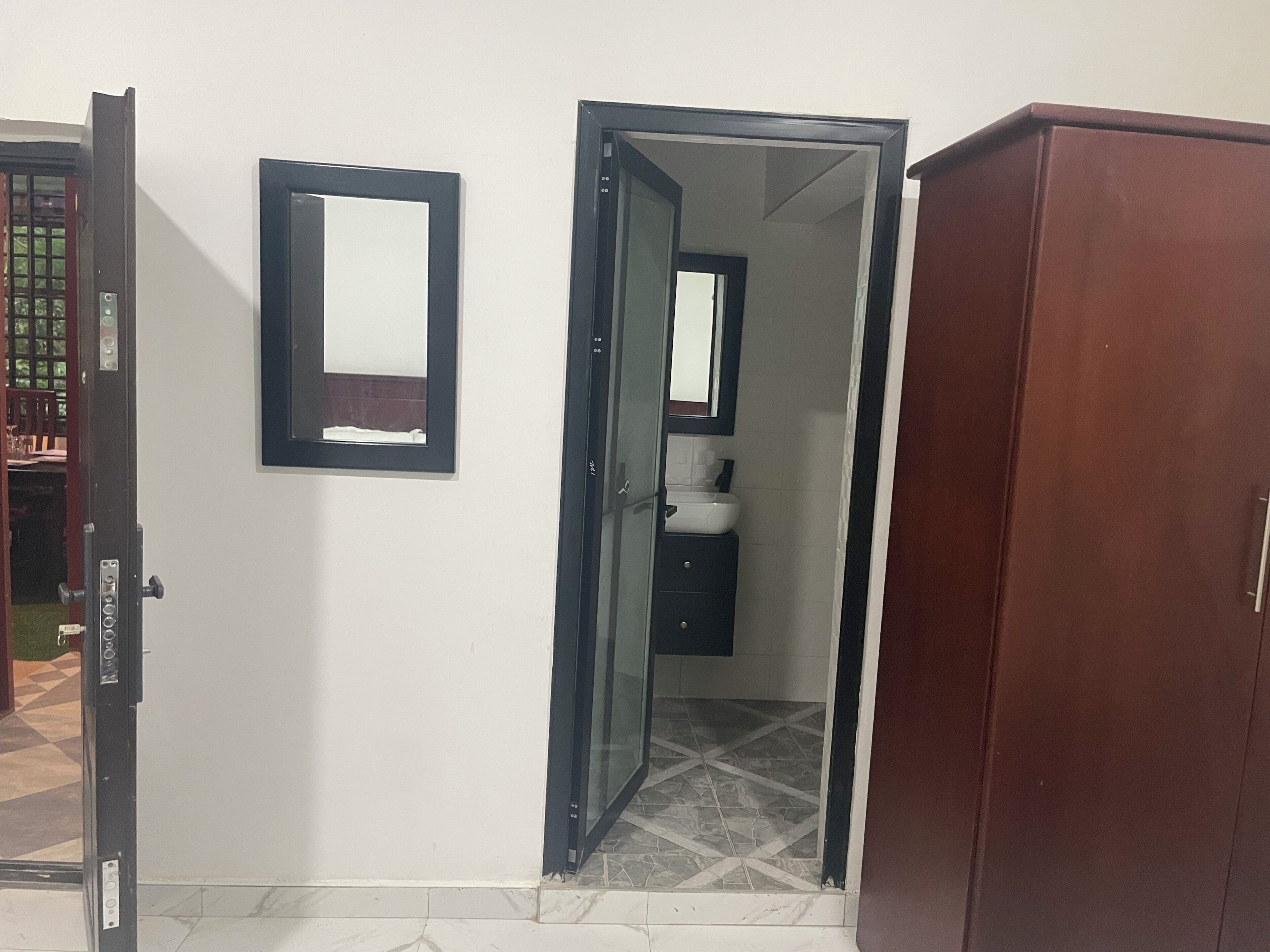 Uma porta aberta que dá para um banheiro com espelho e pia.