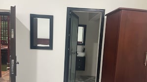 Puerta abierta que da a un baño con espejo y lavamanos.
