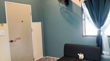 Una habitación con cama, una mesita, un sofá, un ventilador, una ventana con cortinas y una puerta.