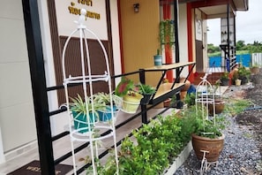 A balcony with potted plants, a wooden bench, and a metal railing. - Rim nam Resort (Nong Khai)