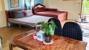Ein Zimmer mit einem Bett, einem Tisch mit Vase und Taschentuchbox sowie einem Stuhl.