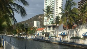 Vista al agua con valla blanca, edificio de techo azul y palmeras.
