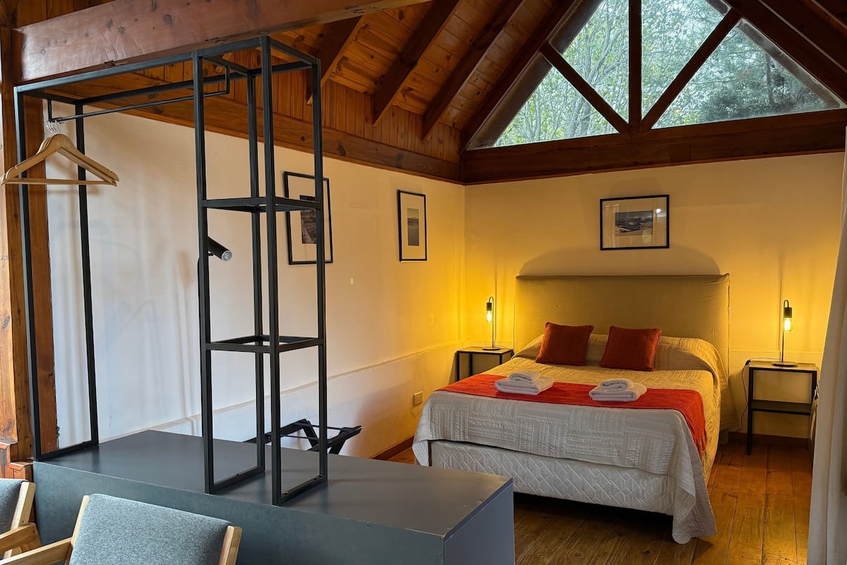Un dormitorio con cama, mesitas de noche, una silla colgante y un armario.
