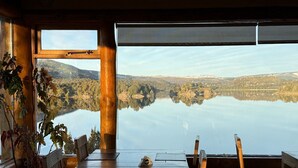 A wooden dining table with chairs, a view of a lake, and a mountain in the background.