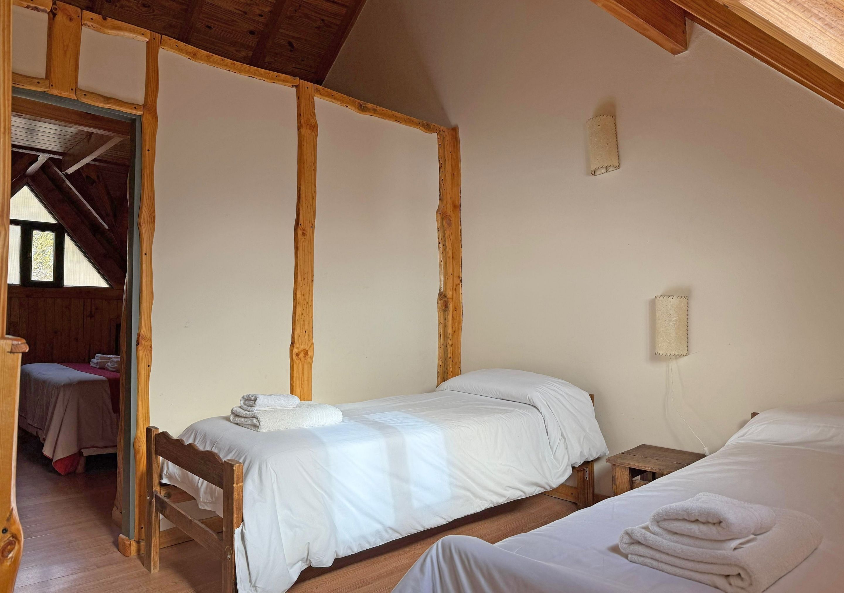 A room with two beds, wooden beams, and a small table.