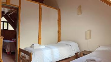 A room with two beds, wooden beams, and a small table.