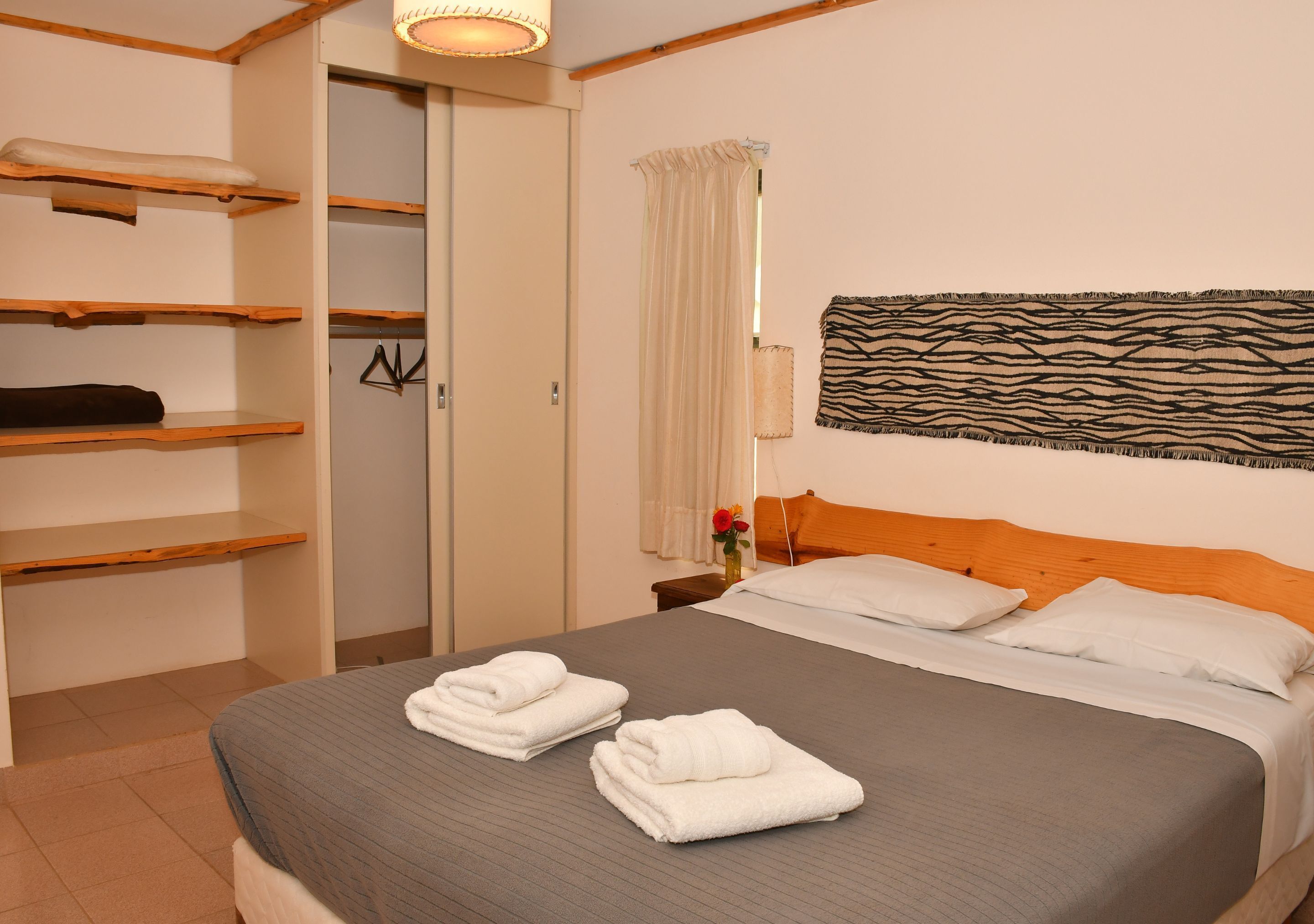 Una habitación de hotel con una cama, un armario, una mesita de noche y una obra de arte colgada en la pared.